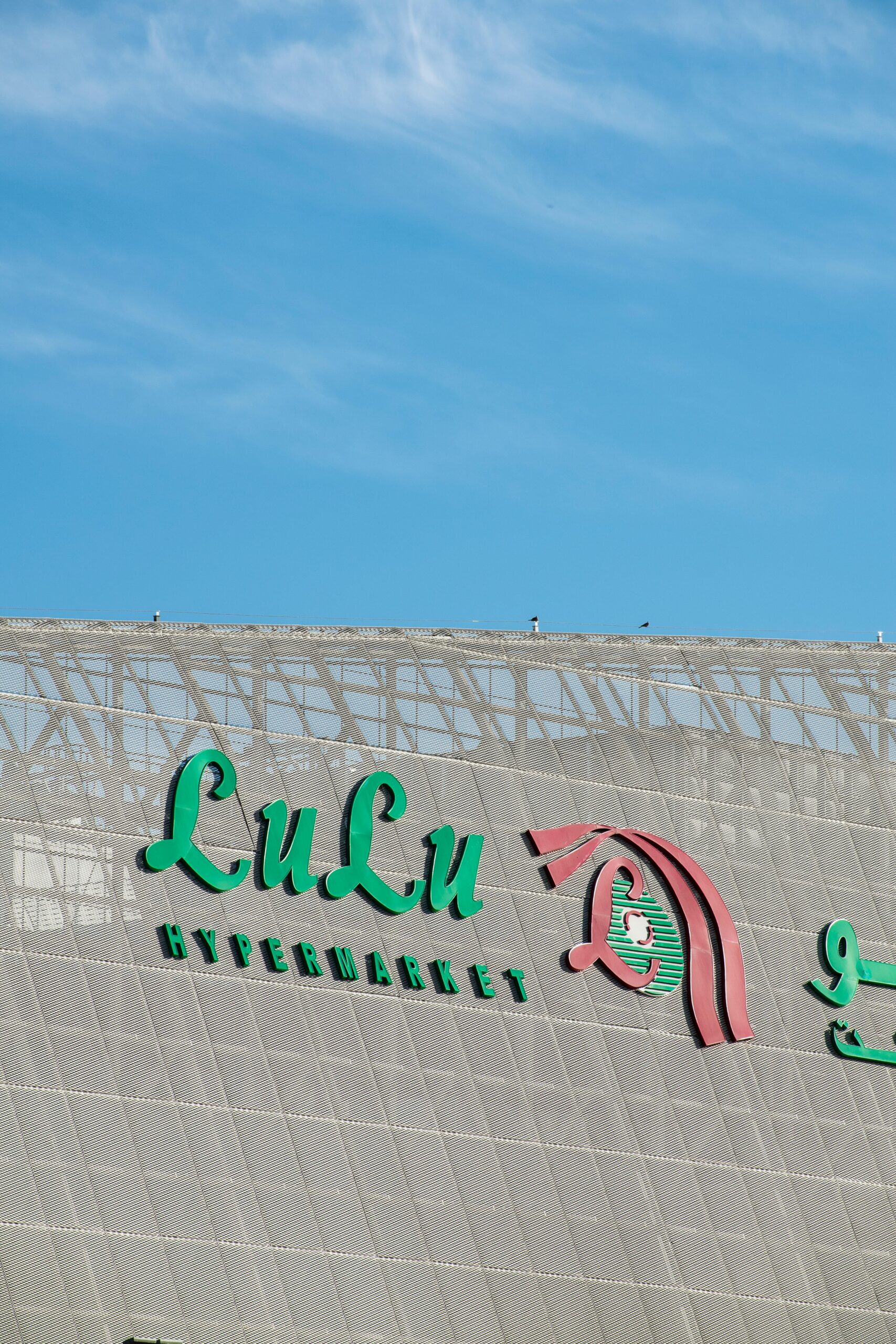 Close-up of the Lulu Hypermarket logo on a building facade under a clear blue sky.